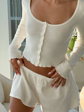 Close-up of a woman wearing a white knit button-front top and matching shorts by Florence by Mills.